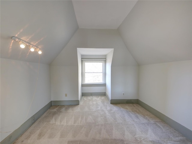 additional living space featuring light colored carpet and vaulted ceiling