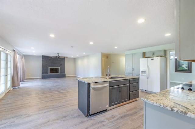 kitchen featuring light stone counters, sink, light hardwood / wood-style flooring, dishwasher, and white fridge with ice dispenser