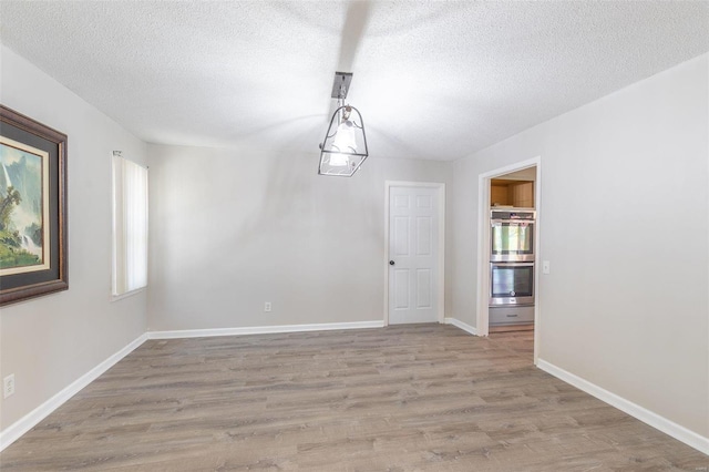 unfurnished dining area featuring light hardwood / wood-style flooring and a textured ceiling