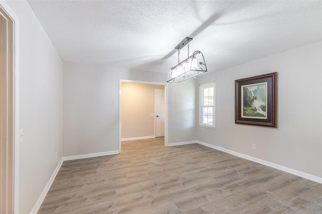 unfurnished room featuring light hardwood / wood-style flooring and a textured ceiling