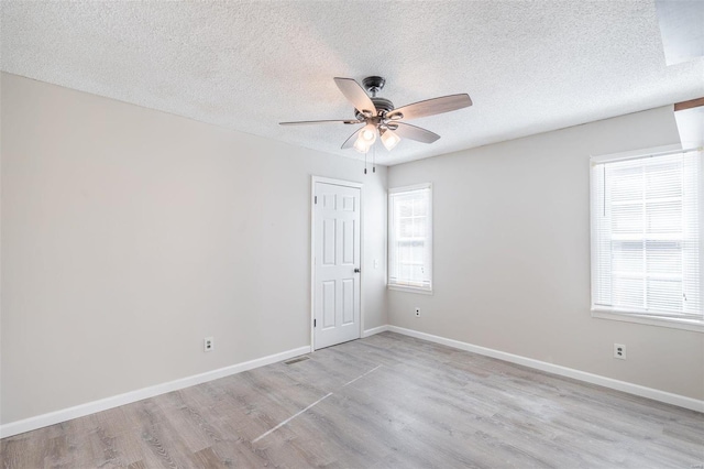 empty room featuring ceiling fan, light hardwood / wood-style flooring, and a textured ceiling