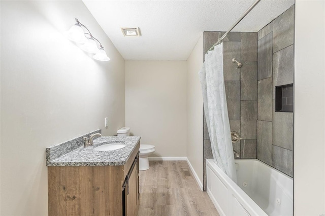 full bathroom with hardwood / wood-style floors, vanity, shower / bath combination with curtain, toilet, and a textured ceiling