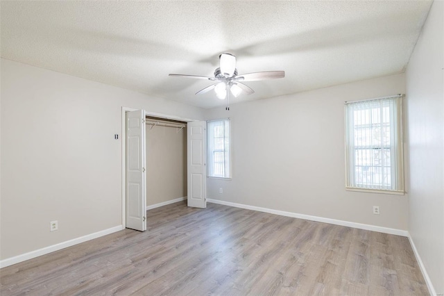 unfurnished bedroom featuring a closet, a textured ceiling, light hardwood / wood-style floors, and ceiling fan