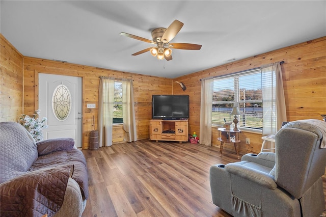 living room featuring ceiling fan, wooden walls, and hardwood / wood-style floors