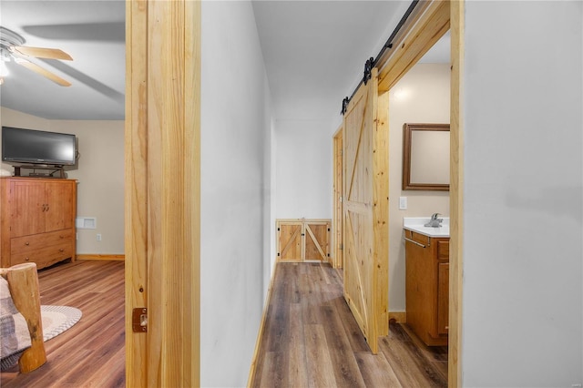 hall featuring wood-type flooring and a barn door