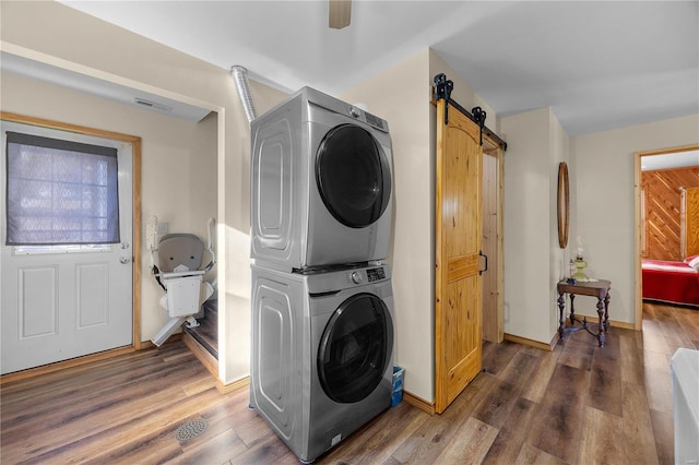 washroom with ceiling fan, a barn door, stacked washer / drying machine, and dark hardwood / wood-style flooring