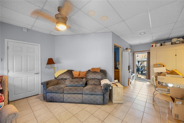 tiled living room with a drop ceiling and ceiling fan