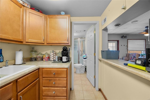 kitchen with sink, light tile patterned floors, and ceiling fan