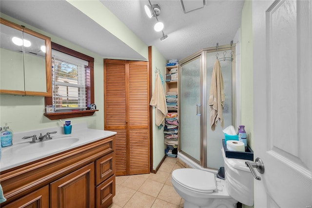 bathroom featuring tile patterned flooring, vanity, a textured ceiling, toilet, and walk in shower