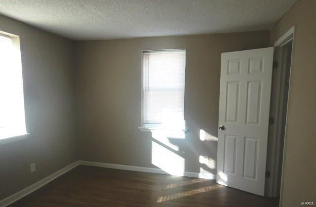 spare room featuring dark wood-type flooring and a textured ceiling