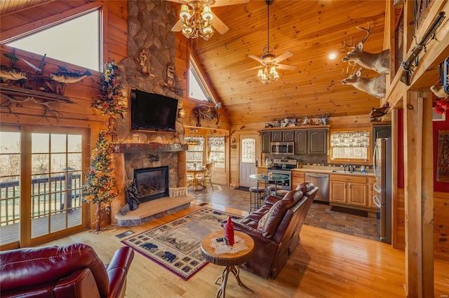 living room featuring sink, a stone fireplace, high vaulted ceiling, wood walls, and light hardwood / wood-style floors