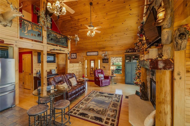 living room featuring light hardwood / wood-style floors, high vaulted ceiling, ceiling fan, and wooden walls