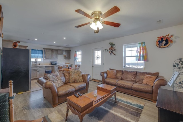 living room with ceiling fan, light hardwood / wood-style flooring, and sink