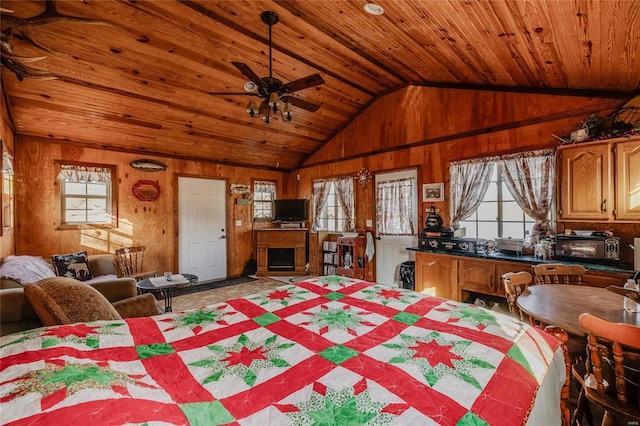 dining area with vaulted ceiling, ceiling fan, wood walls, and wood ceiling