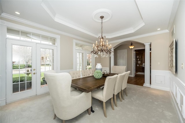 carpeted dining space featuring decorative columns, french doors, and a healthy amount of sunlight