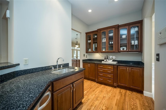 bar featuring dishwasher, light wood-type flooring, decorative light fixtures, and sink