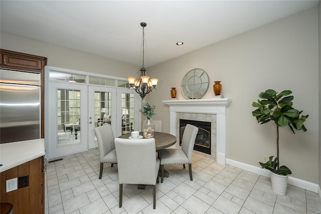 tiled dining space featuring a tile fireplace, french doors, and a notable chandelier