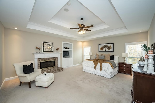 bedroom featuring a raised ceiling, ceiling fan, light colored carpet, and a fireplace