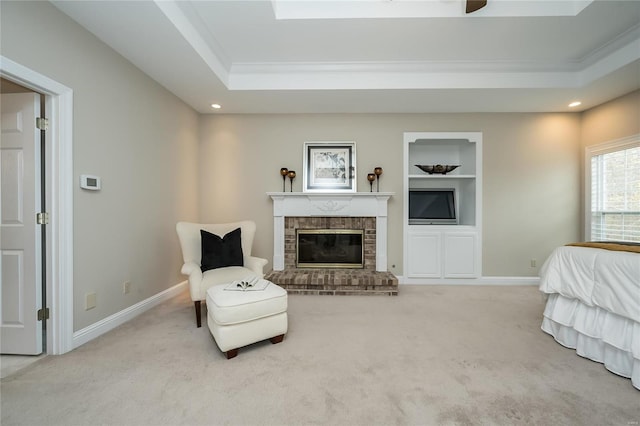 bedroom featuring crown molding, light carpet, a tray ceiling, and a brick fireplace