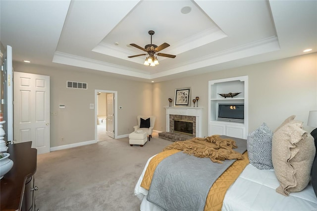 bedroom featuring a raised ceiling, ceiling fan, a fireplace, and light carpet