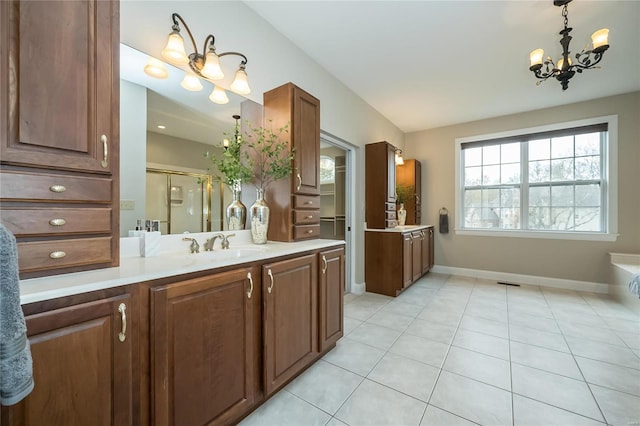 bathroom featuring tile patterned flooring, vanity, a shower with door, and an inviting chandelier