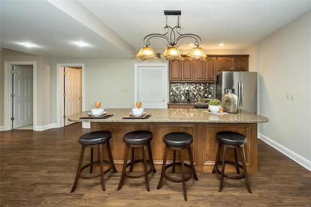 kitchen with a kitchen breakfast bar, dark hardwood / wood-style flooring, a notable chandelier, stainless steel fridge with ice dispenser, and a center island