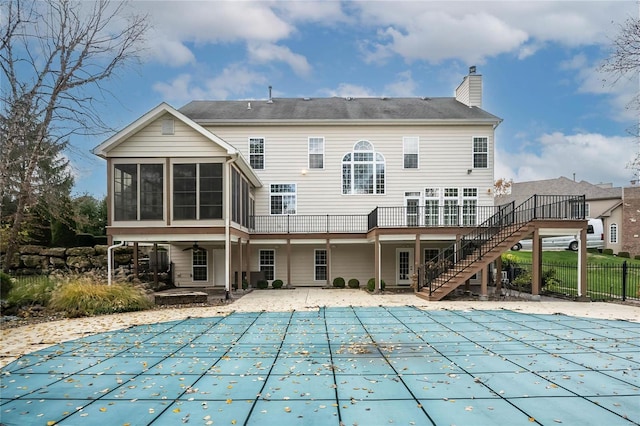 rear view of property with a covered pool, a patio area, and a sunroom