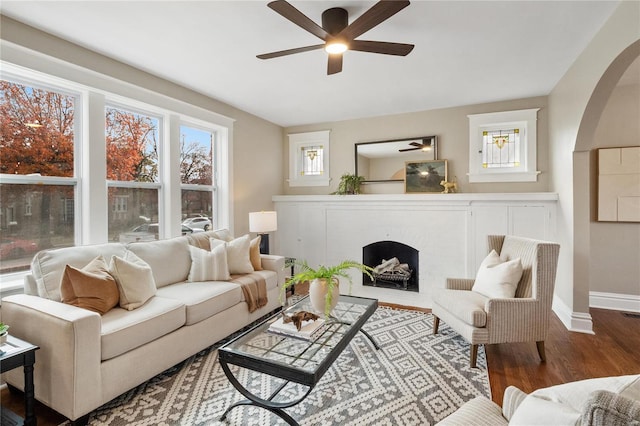 living room featuring wood-type flooring, a fireplace, and ceiling fan