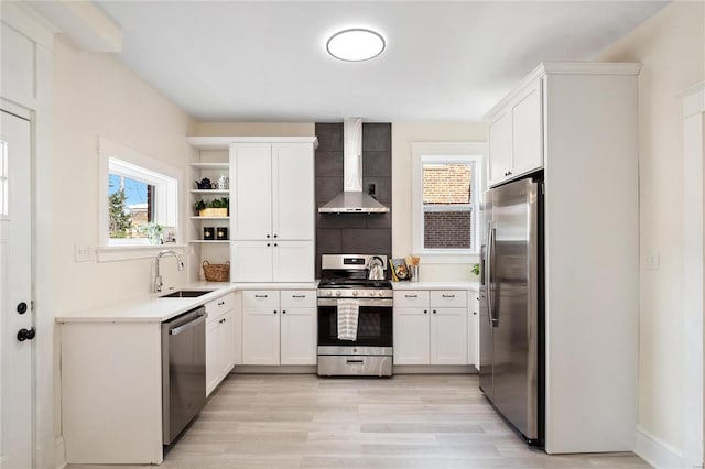 kitchen featuring sink, light hardwood / wood-style flooring, white cabinetry, stainless steel appliances, and wall chimney exhaust hood