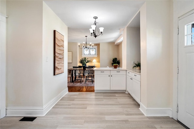 hallway featuring an inviting chandelier and light wood-type flooring