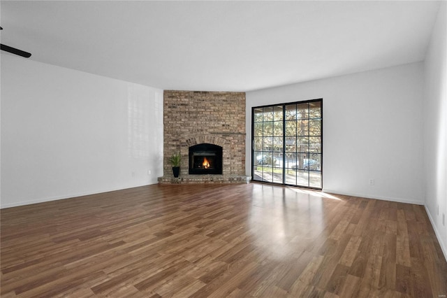 unfurnished living room featuring hardwood / wood-style flooring and a brick fireplace