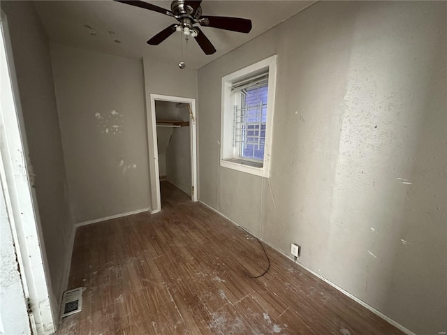 unfurnished bedroom featuring ceiling fan, dark hardwood / wood-style flooring, and a closet