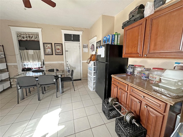 kitchen featuring black fridge, ceiling fan, a textured ceiling, and light tile patterned floors