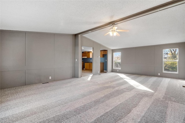 carpeted spare room with a textured ceiling, ceiling fan, and lofted ceiling