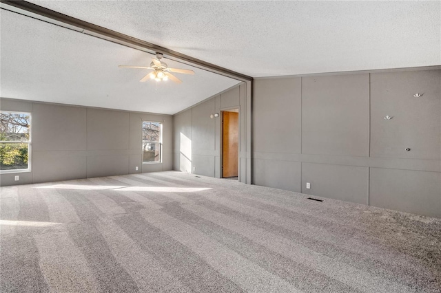 carpeted empty room featuring a textured ceiling, ceiling fan, and vaulted ceiling