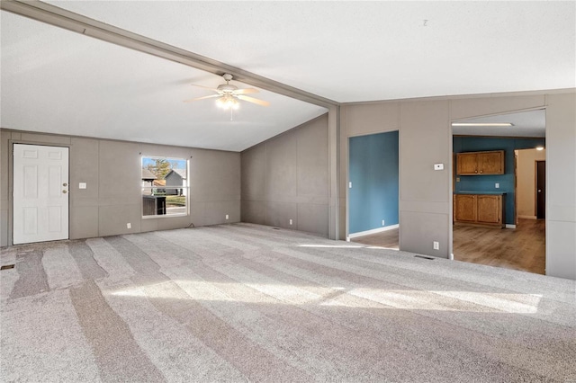 unfurnished living room with ceiling fan, light colored carpet, and lofted ceiling with beams