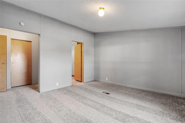 unfurnished bedroom with a textured ceiling, light colored carpet, and a closet