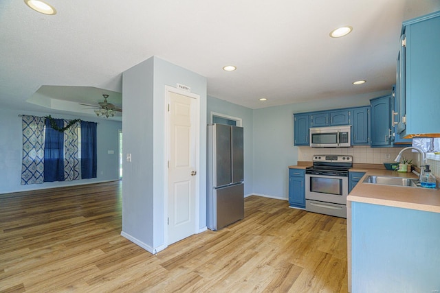 kitchen featuring blue cabinetry, appliances with stainless steel finishes, light wood-type flooring, and sink