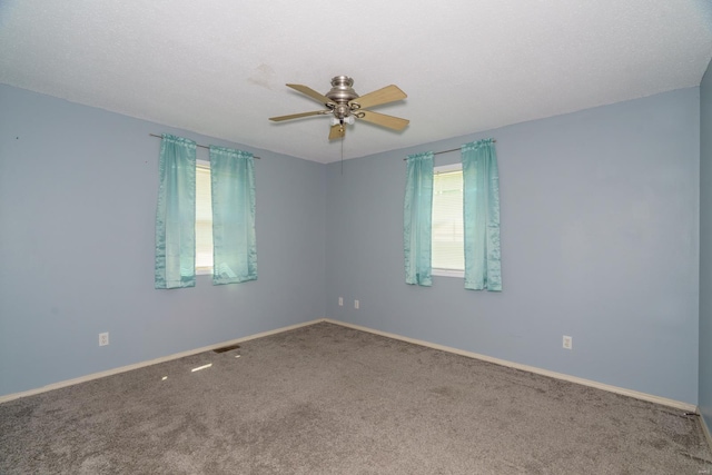 carpeted empty room featuring a wealth of natural light and ceiling fan