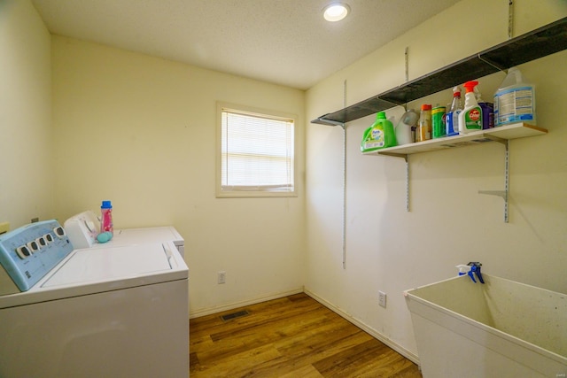 washroom with separate washer and dryer, hardwood / wood-style flooring, and a textured ceiling