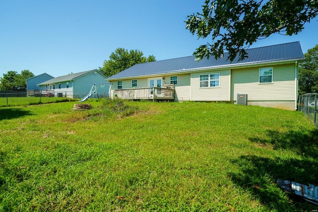 rear view of house with a fire pit, a deck, and a lawn