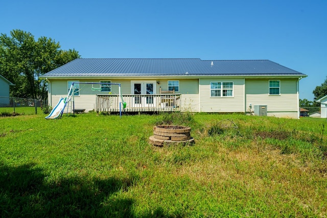 back of house with a lawn, a fire pit, a wooden deck, and central AC unit