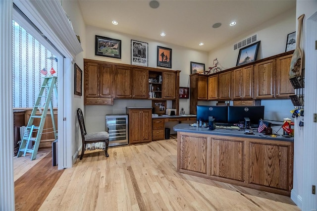 kitchen featuring light wood-type flooring, built in desk, and beverage cooler