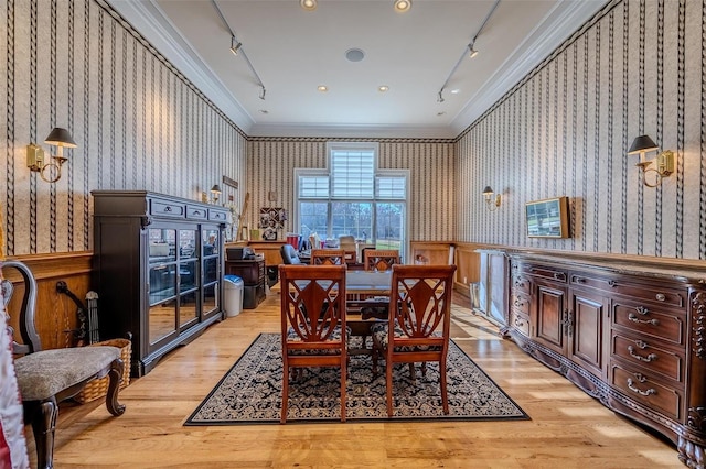 dining space featuring light hardwood / wood-style floors, track lighting, and ornamental molding