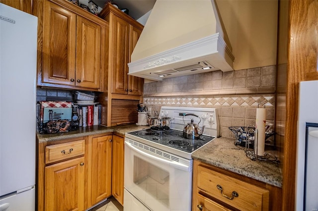 kitchen featuring decorative backsplash, custom range hood, stone countertops, and white appliances