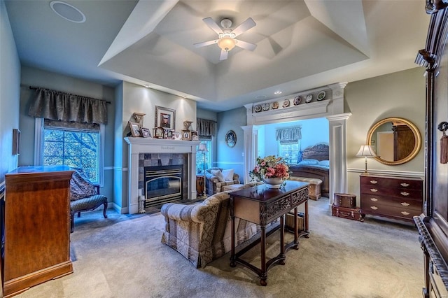 carpeted living room featuring a tile fireplace, a tray ceiling, and ceiling fan