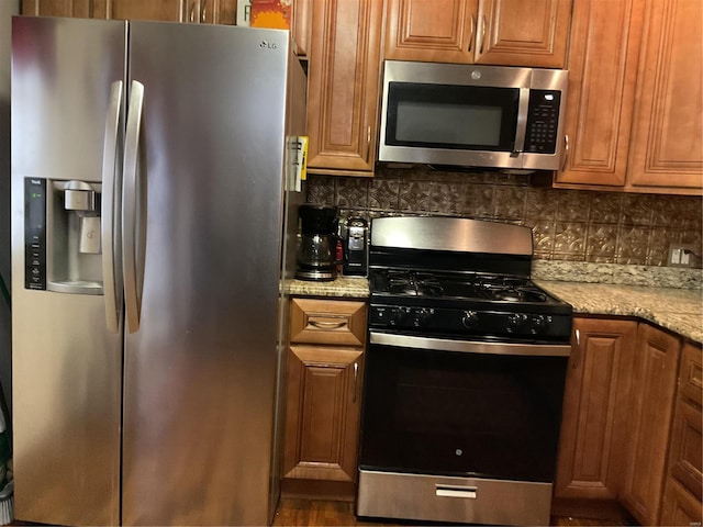 kitchen featuring light stone counters, appliances with stainless steel finishes, and tasteful backsplash