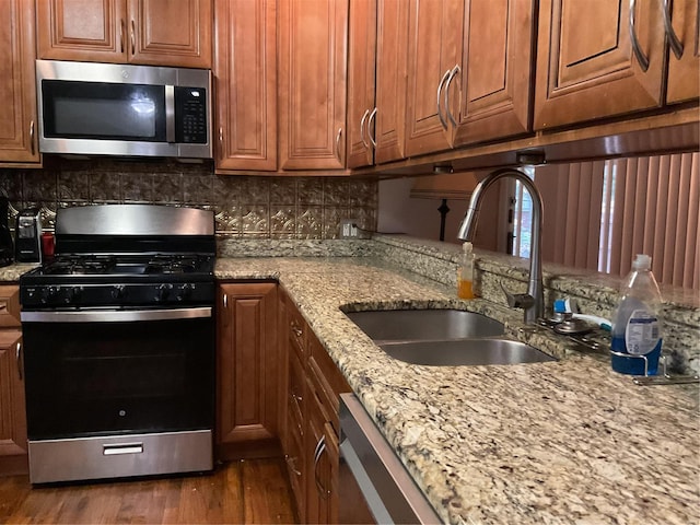 kitchen featuring light stone counters, sink, appliances with stainless steel finishes, and tasteful backsplash