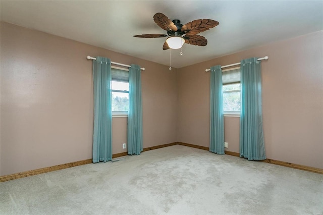 carpeted spare room with ceiling fan and plenty of natural light