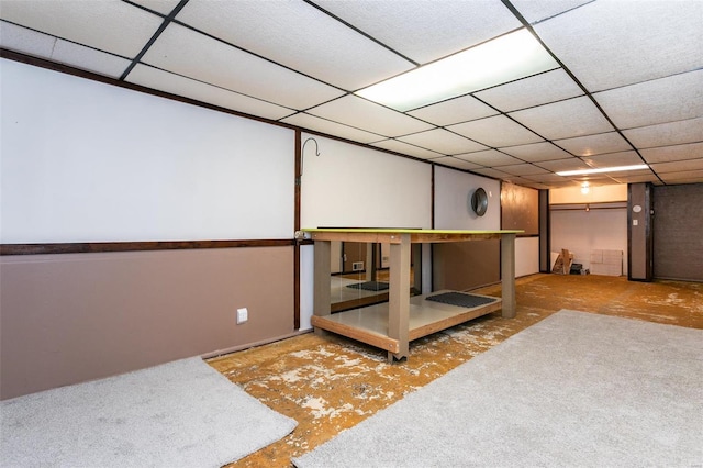 basement with a paneled ceiling and light carpet